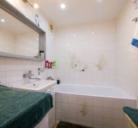 Badezimmer in einer 3-Zimmer-Wohnung mit Badewanne, Waschbecken und weißen Fliesen.