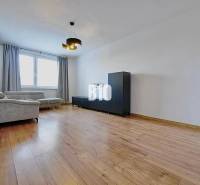 Wohnzimmer in einer 3-Zimmer-Wohnung mit einem bequemen Sofa und einem Boden in Holzoptik.