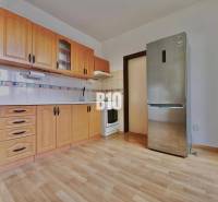 Küche mit Holzschränken und Holzboden in einer 3-Zimmer-Wohnung.