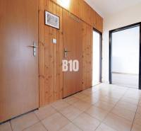 Flur in einer 3-Zimmer-Wohnung mit Fliesenboden, Holzverkleidung und Eingängen zu weiteren Räumen.