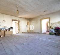 Unordentliches Zimmer in einem Einfamilienhaus mit Holzboden und Baumaterial.