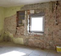 Ein Zimmer in einem Einfamilienhaus mit Ziegelwänden und einem Eimer auf dem Boden.