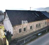 Ein Einfamilienhaus in Bytča mit abgenutztem Dach und Putz, neben der Hauptstraße.