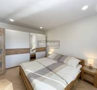 Schlafzimmer mit Holzboden in einer Einzimmerwohnung, helles Bett und Kleiderschrank.