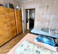 Schlafzimmer in einer 3-Zimmer-Wohnung mit einem großen Holzkleiderschrank und einem Boden mit Holzdekor.