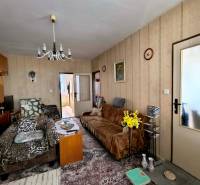 Wohnzimmer in einer 3-Zimmer-Wohnung mit Sesseln, Blumen und einem Vintage-Kronleuchter.