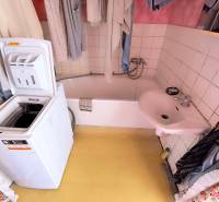 Badezimmer mit Waschbecken, Badewanne und Waschmaschine in einer 3-Zimmer-Wohnung.