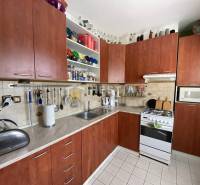 Küche in einer 2-Zimmer-Wohnung mit Holzschränken und weißen Fliesen.
