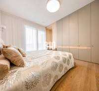 Schlafzimmer in einer 3-Zimmer-Wohnung mit Bett, Einbauschrank und Boden in Holzoptik.