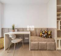 Arbeitsbereich mit Stuhl, Tisch, Bank und Regalen in einer 3-Zimmer-Wohnung.