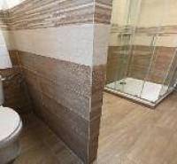Badezimmer in einer 2-Zimmer-Wohnung mit Toilette und Fliesen in Holzoptik.