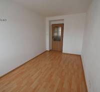 Ein Zimmer in einer 2-Zimmer-Wohnung mit einem Boden in Holzoptik und weißen Wänden.