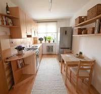 Küche in einer 2-Zimmer-Wohnung mit Holzboden, Esstisch und Regale.