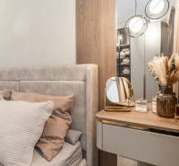 Schlafzimmer in einer 3-Zimmer-Wohnung mit Bett, Spiegel und dekorativen Elementen.
