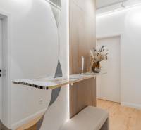 Flur in einer 3-Zimmer-Wohnung mit einem minimalistischen Tisch, einem Spiegel und einem Boden mit Holzdekor.