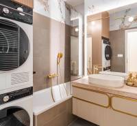 Badezimmer in einer 3-Zimmer-Wohnung mit Badewanne, Waschbecken, Trockner und eleganten goldenen Accessoires.