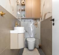 Toilette mit Waschbecken, goldener Wasserhahn und Fliesen mit Marmormuster in einer 3-Zimmer-Wohnung.