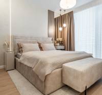 Helles Schlafzimmer mit bequemem Bett, beigefarbenen Vorhängen und Holzbodenoptik.