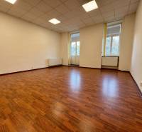 Ein leeres Büro mit Holzboden und großen Fenstern.