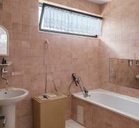 Badezimmer in einem Einfamilienhaus mit Fliesen und Badewanne; ein Korb aus Weide neben dem Waschbecken.