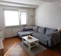 Wohnzimmer einer Zweizimmerwohnung mit Ecksofa und Tisch auf einem Boden mit Holzdekor.