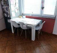 Küche einer 2-Zimmer-Wohnung mit Esstisch, weißen Stühlen und Fenster.