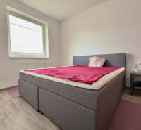 Schlafzimmer in einer 2-Zimmer-Wohnung mit Bett, Holzboden und Nachttisch.