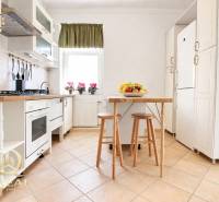 Küche in einer Einzimmerwohnung mit weißen Schränken und einem Tisch mit Obst.