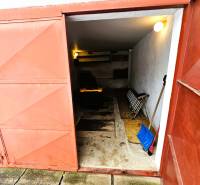 Eine Garage in einem Einfamilienhaus in Kameňany mit offenen Metalltüren und Werkzeugen.