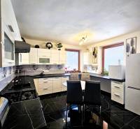 Eine Küche in einem Einfamilienhaus mit glänzenden schwarzen Fliesen und weißen Möbeln.