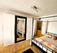 Ein Schlafzimmer in einem Einfamilienhaus mit einem Bett, einem Teppich und einem Schrank mit Spiegel.