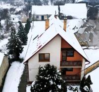 Ein Einfamilienhaus in Kameňany, bedeckt mit Schnee, mit Blick auf verschneite Felder und Hügel.