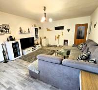 Wohnzimmer in einem Einfamilienhaus mit Holzboden, grauem Sofa und moderner Beleuchtung.