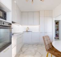 Küche in einer 3-Zimmer-Wohnung mit weißen Schränken und Steinboden.