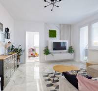 Wohnzimmer in einer 3-Zimmer-Wohnung mit dekorativem Tisch und Fernseher an der Wand.