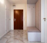 Eingangsflur in einer 3-Zimmer-Wohnung mit Fliesenboden und gepolsterter Bank.