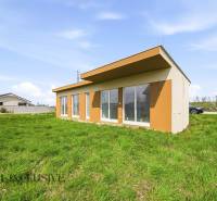 Ein Ferienhaus in Vojka nad Dunajom mit Rasen und verglasten Wänden.