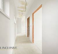 Ein heller Flur in einer Hütte mit rohem Boden, weißen Wänden, sichtbaren Kabeln.