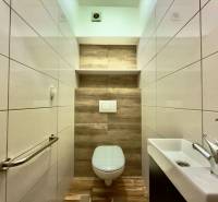 Badezimmer in einer 2-Zimmer-Wohnung mit Holzboden und weißen Fliesen.