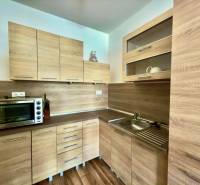 Küche mit Einbauschränken und Boden in Holzoptik in einer Zweizimmerwohnung.
