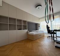 Ein Zimmer in einer 4-Zimmer-Wohnung mit einem Bett, einem Tisch und einem Boden in Holzoptik.