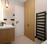 Badezimmer mit Schrank, weißem Waschbecken und schwarzem Leiterheizkörper in einer 4-Zimmer-Wohnung.