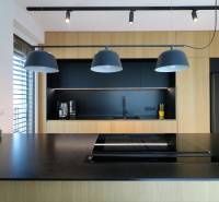 Küche in einer 4-Zimmer-Wohnung mit schwarzen und hölzernen Elementen, Hängelampen.
