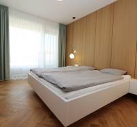 Schlafzimmer in einer 4-Zimmer-Wohnung mit Holzboden, weißen Möbeln und einem großen Fenster.
