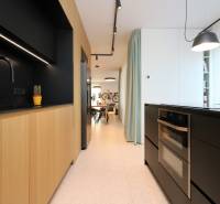 Küche in einer 4-Zimmer-Wohnung mit Holzelementen und schwarzen Accessoires.