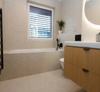 Badezimmer in einer 4-Zimmer-Wohnung mit Badewanne, Waschbecken und Holzdekor des Schranks.