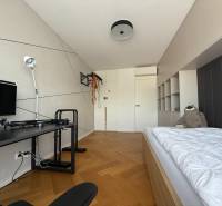 Ein Zimmer in einer 4-Zimmer-Wohnung mit einem Bett, einem Tisch und einem Boden in Holzoptik.