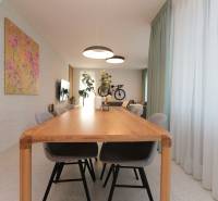 Esszimmer mit großem Holztisch, Stühlen und Vorhängen in einer Vierzimmerwohnung.