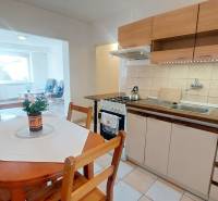 Küche in einer 2-Zimmer-Wohnung mit Sitzgelegenheit, hellem Boden und Esstisch.