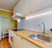Küche in einer Einzimmerwohnung mit weißen Schränken und einem Boden in Holzoptik.